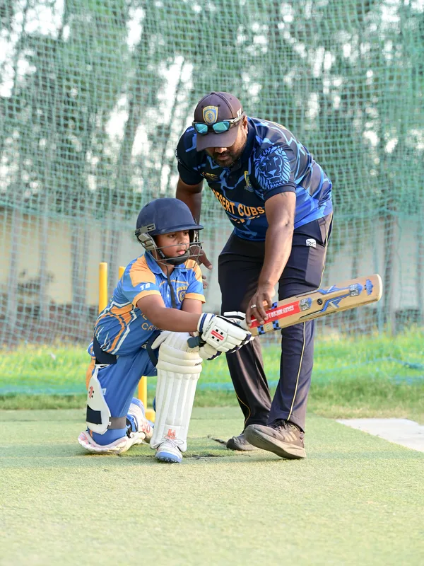 Desert Cubs coach guiding a beginner through a front-foot batting drill at SES